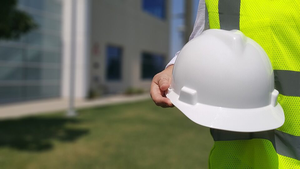 mining safety equipment worker wearing high-visibility vest, holding hard hat
